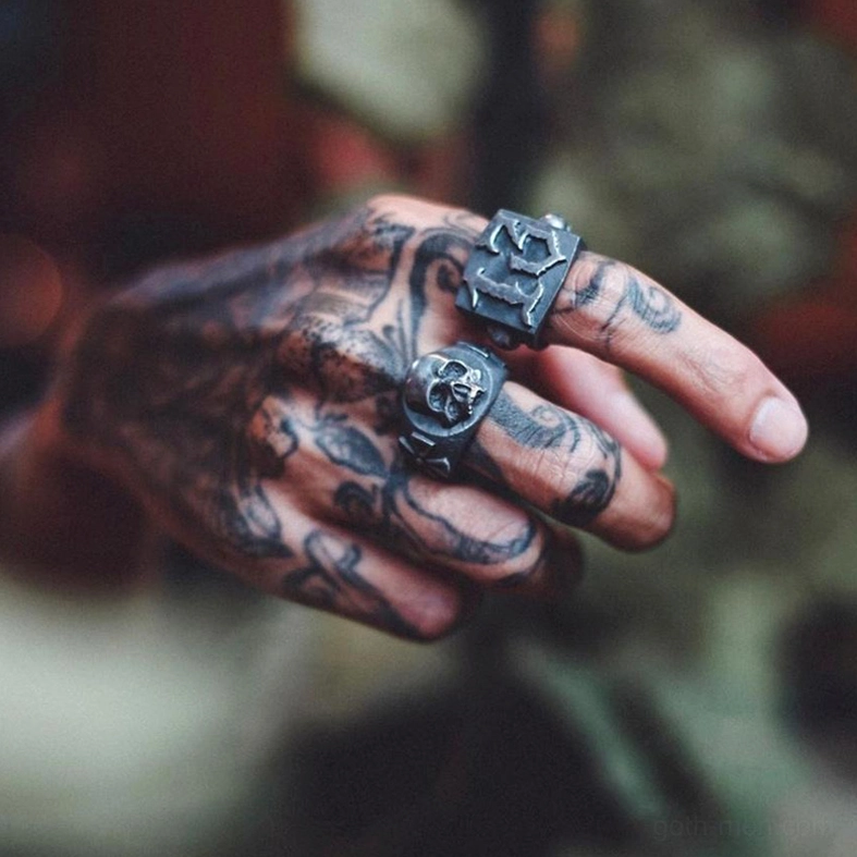 Vintage gothic punk rings worn on tattooed male hand close-up side view