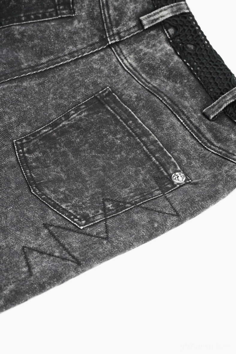 Close up front detail of gothic punk shorts showing rear pocket metal button triangle stitching and acid washed denim finish