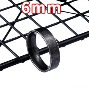 6mm width gothic stainless steel ring displayed on black grid shelf, three-quarter angle showing slim band design with aged matte black finish, minimalist jewelry style