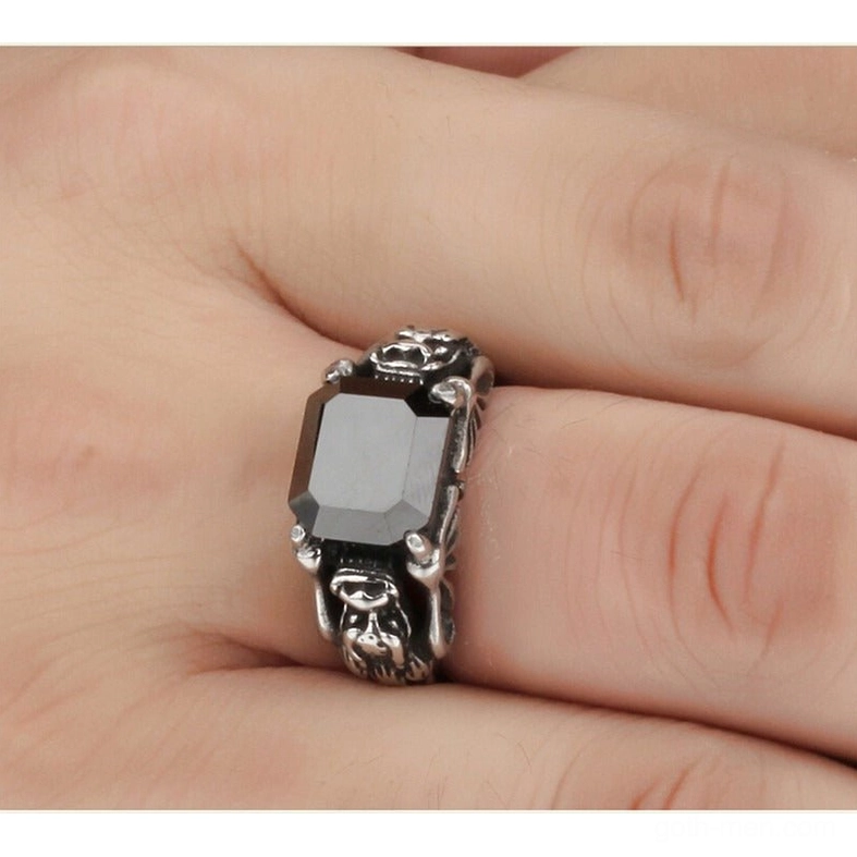 Punk gothic skull ring on human hand showing wearable size and vintage carved band design with dark gemstone