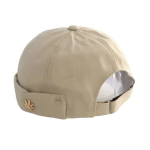 Beige cotton brimless cap with maple leaf rivet decoration, rear perspective showing adjustable strap and solid texture