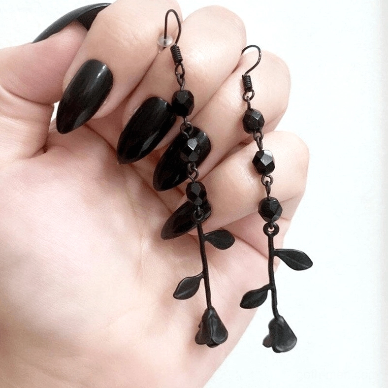 Black gothic beaded drop earrings with mixed faceted and teardrop beads, close-up front view on female hand