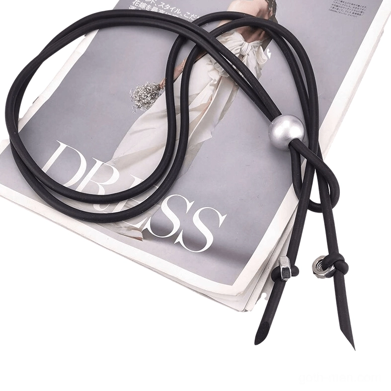 Coiled black rubber cord gothic necklace with silver sphere and knotted end fasteners, fashion magazine backdrop