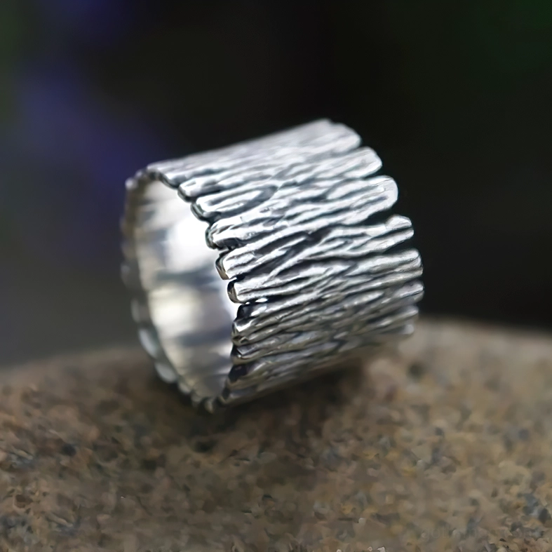 Side profile of Viking rune ring on stone surface showing wood grain texture, split ring opening, and polished inner wall detail