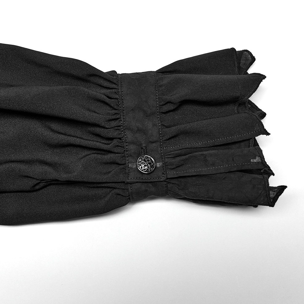 Close-up of black gothic shirt cuff showing ruffled flared design, vintage decorative button, and woven fabric texture