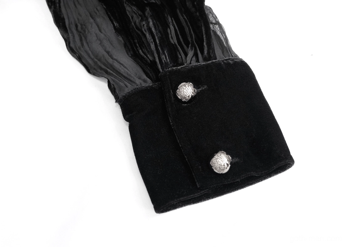 Close-up detail of black velvet shirt cuff with two embossed silver buttons and sheer sleeve fabric