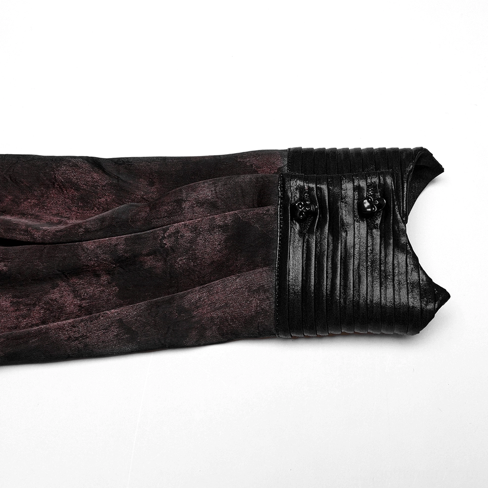 Close-up detail of gothic shirt cuff showing pleated leather trim, functional skull-shaped button, and wine-red floral fabric contrast