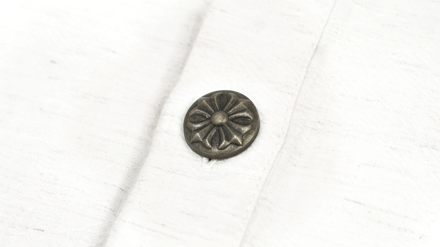 Embossed vintage metal button close-up on textured cotton gothic shirt fabric
