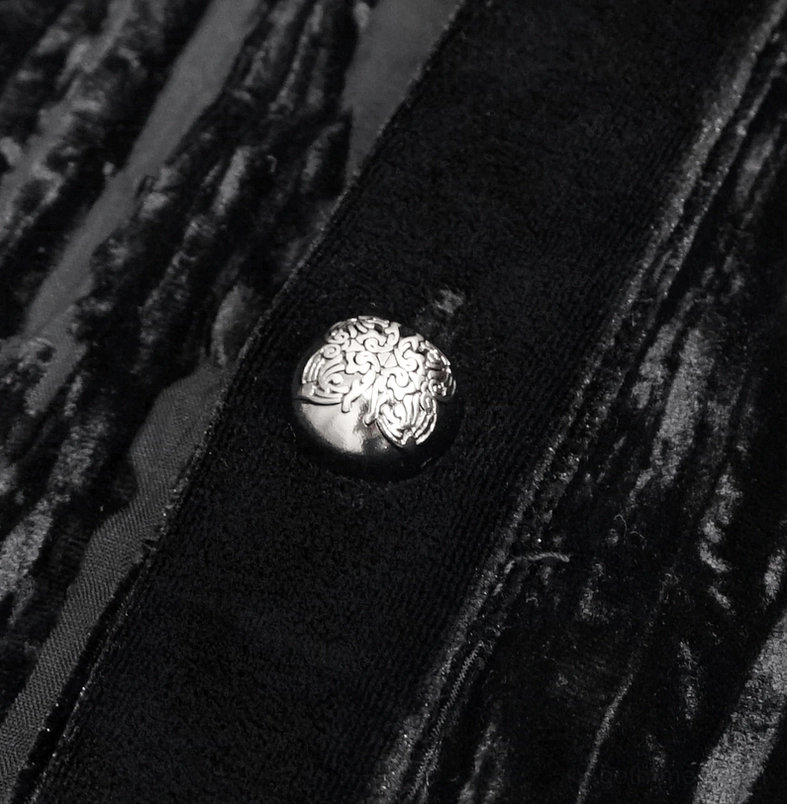 Macro close-up of ornate embossed silver button on smooth black velvet fabric