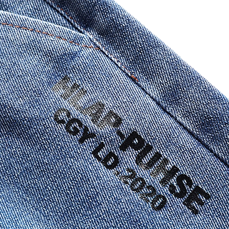 Detailed close-up of embossed letter print on dark denim shorts fabric with visible stitching