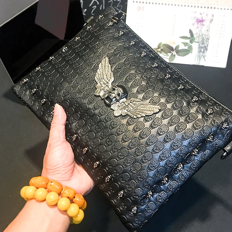 Handheld gothic skull bag with silver winged emblem hardware - paired with alternative jewelry