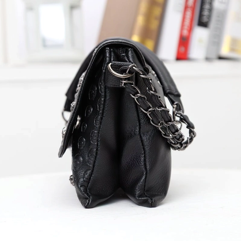 Side rear angle of compact black leather gothic shoulder bag with chain hardware and structured shape