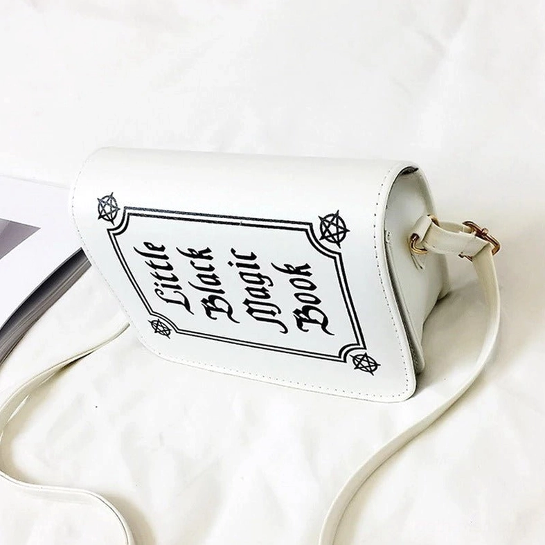 White gothic crossbody bag side profile showing three-quarter angle and hardware details on bedding