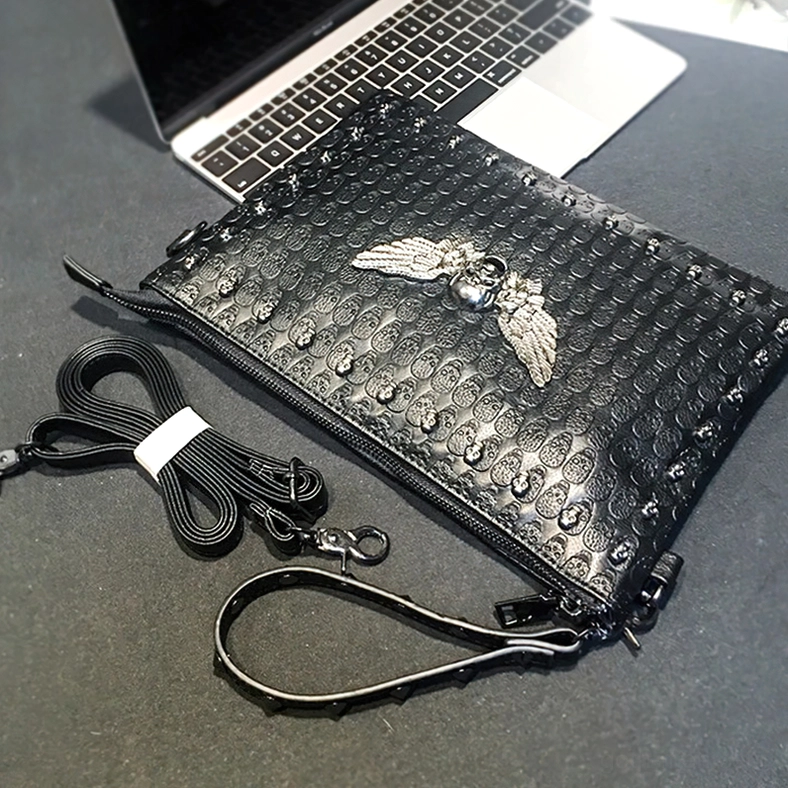 Dark gothic handbag on office desk with laptop - top down flat lay showing embossed skull texture