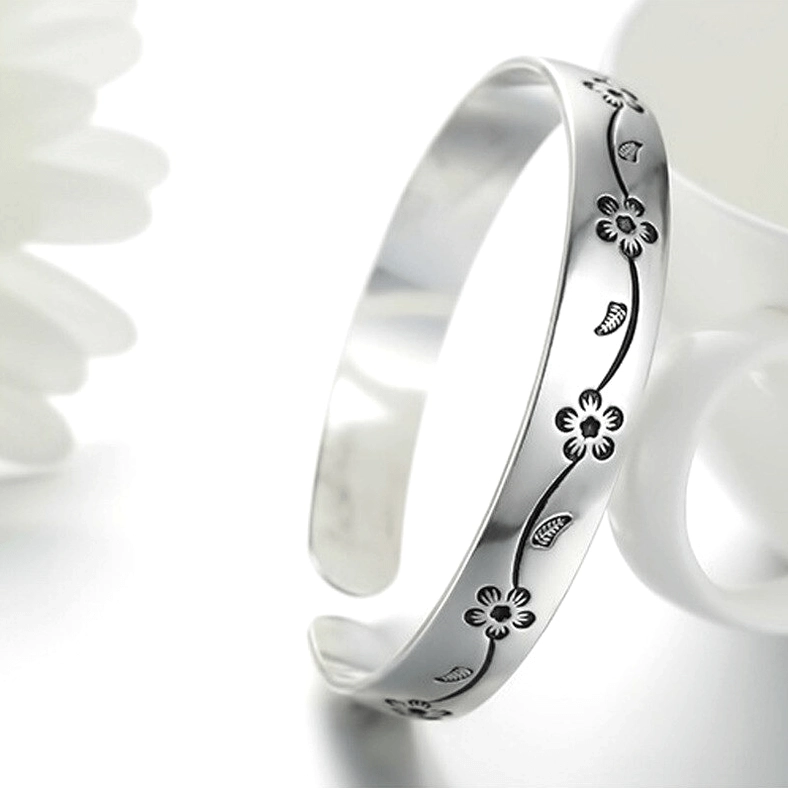 Vintage silver gothic bangle with oxidized floral and leaf motifs next to ceramic mug, styled flat lay photography