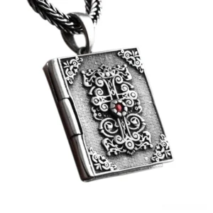 Sterling silver gothic bible locket pendant with ornate cross and embossed scrollwork, three-quarter view showing detailed religious book design