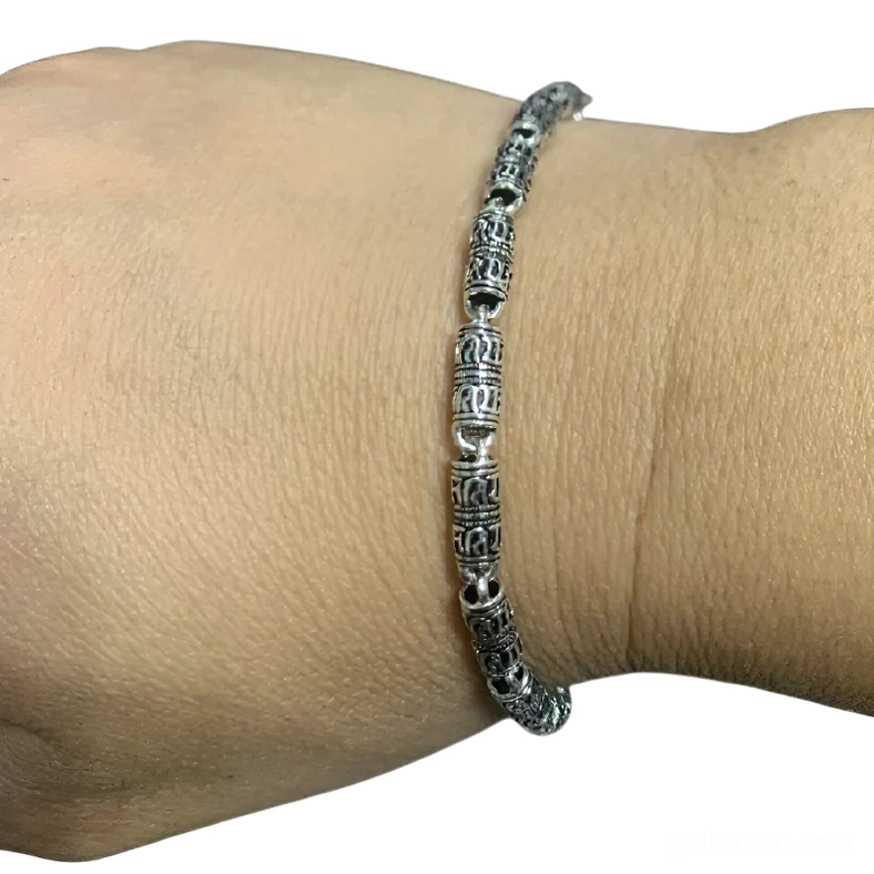Gothic engraved silver bracelet worn on wrist, close-up side view showing vintage distressed metal finish and carved details