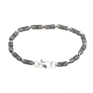 Gothic silver engraved cylindrical bracelet with occult symbols in aged sterling silver, overhead flat lay view with hook clasp