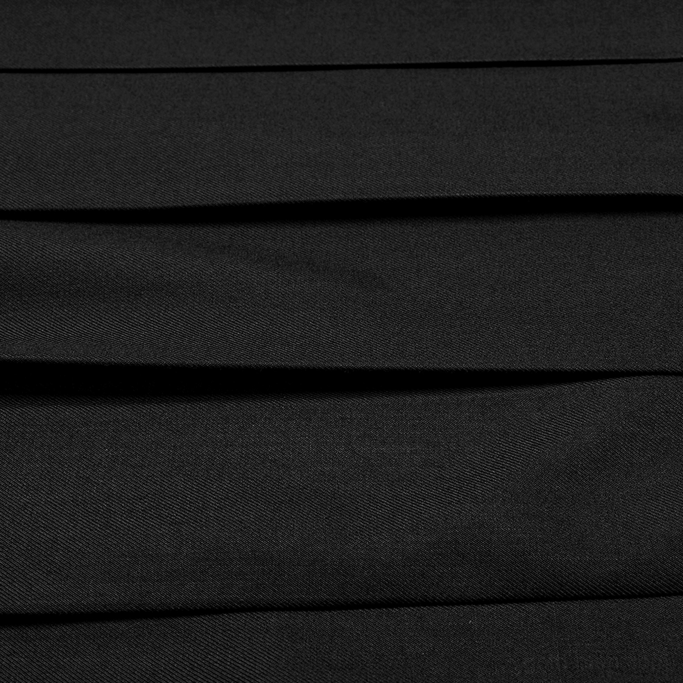 Close-up detail of neat uniform pleats on black gothic asymmetrical skirt showing matte fabric texture