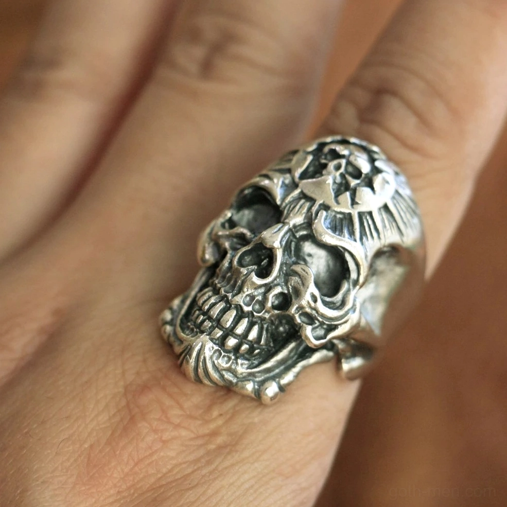 Worn gothic skull ring on finger showing natural patina and detailed skull carving in daylight