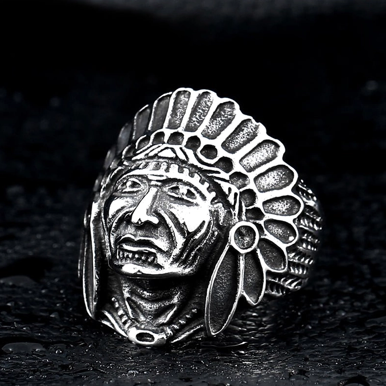 All-silver gothic skull chief ring with intricate tribal feather carving, three-quarter angle view on dark background