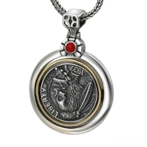 Double-sided gothic skull coin pendant in polished sterling silver with red gemstone accent, front overhead view showing intricate engraved skull and feather design