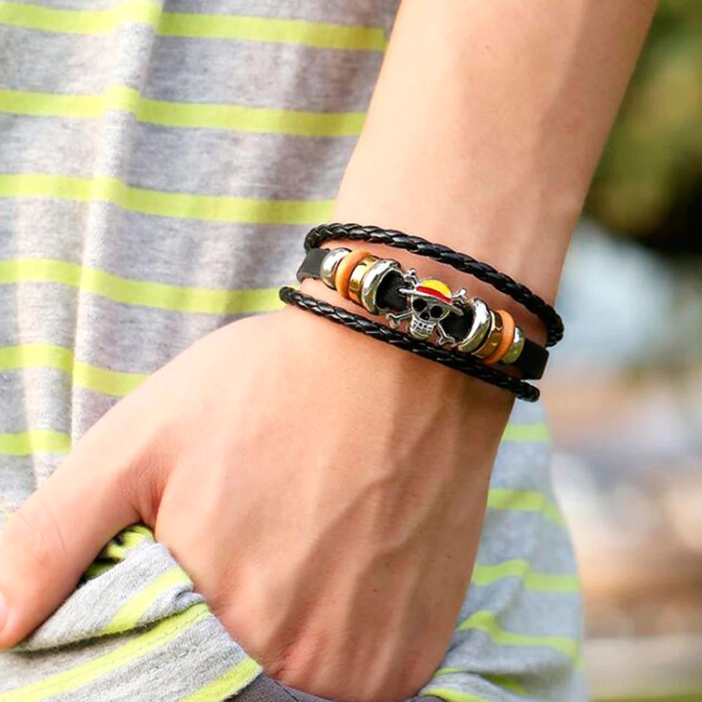 Black braided leather gothic skull bracelet worn on male wrist - multi-layer leather wrap design showcasing punk aesthetic in outdoor casual setting