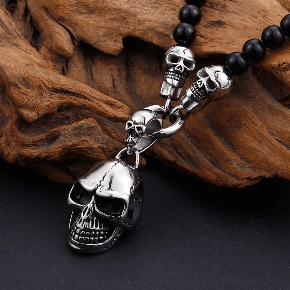Skull pendant necklace on driftwood background dark gothic aesthetic black beads stainless steel