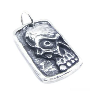 Front oblique view of embossed ghost skull dog tag pendant in matte silver stainless steel with textured details on white background