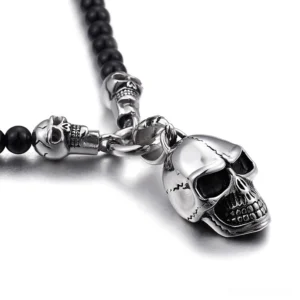 Overhead close-up view of polished stainless steel skull pendant with black glass beads gothic necklace