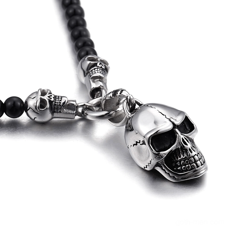Overhead close-up view of polished stainless steel skull pendant with black glass beads gothic necklace