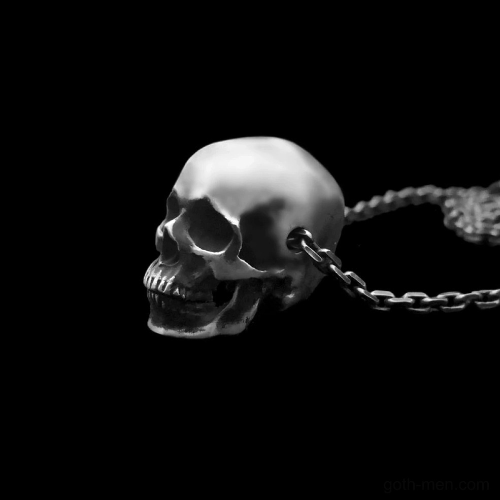 Silver-toned skull pendant side profile view against black background emphasizing depth and design