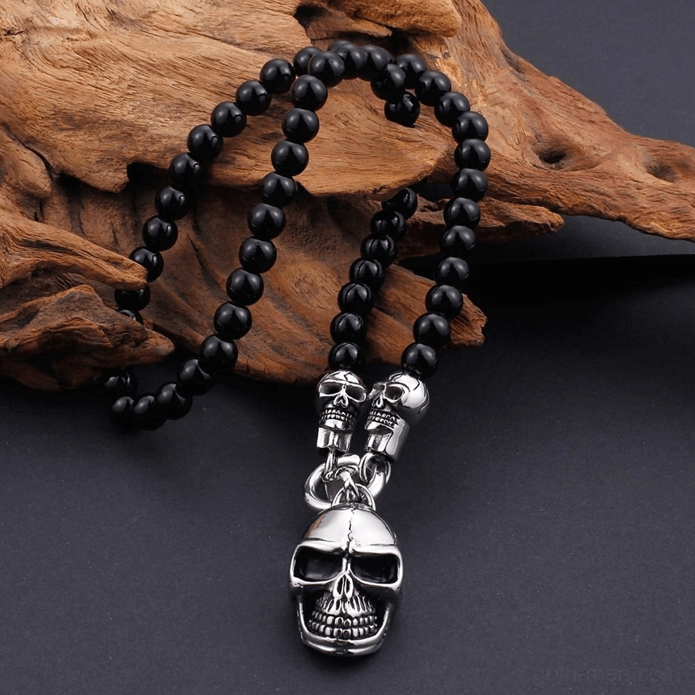 Vertical close-up skull pendant gothic necklace multiple skull details stainless steel beads driftwood