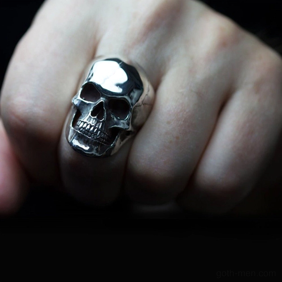 Dark silver skull ring worn on hand close-up showing compact gothic jewelry design and metal band fit