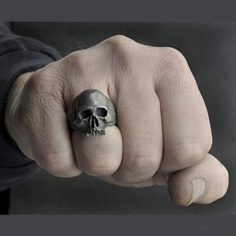 Dark gray gothic skull ring on male hand fist view showing compact band shape and weathered metal