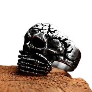Gothic skull signet ring oblique view showcasing weathered patina and skeletal hand design on wooden surface