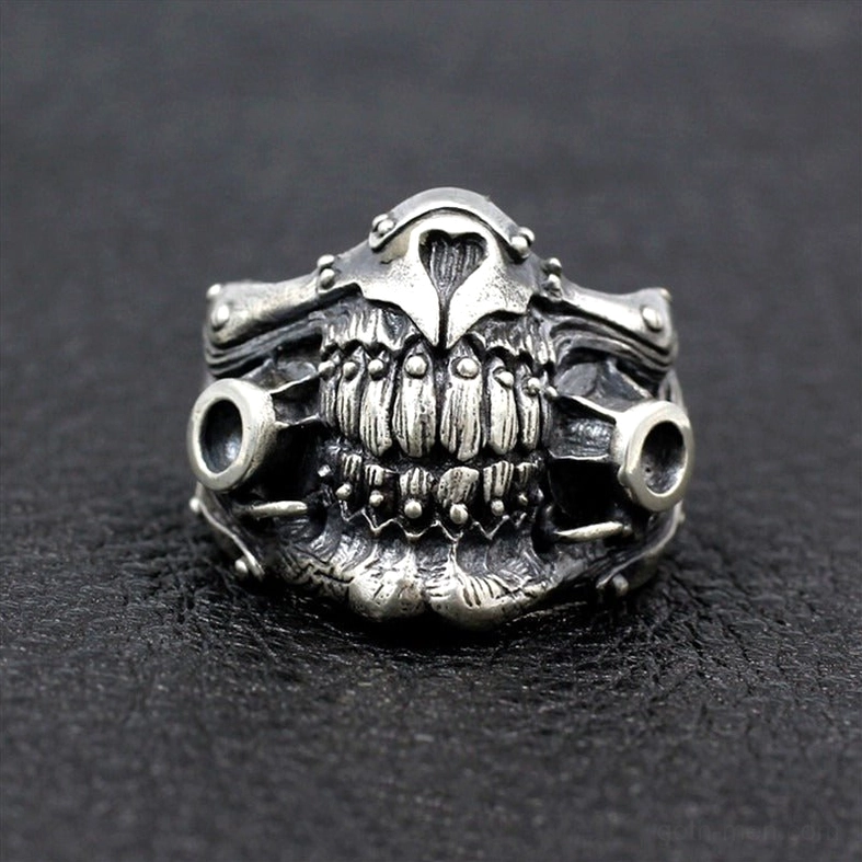 Low angle front view of skull mask ring emphasizing dual hollow side ports and skeletal architecture