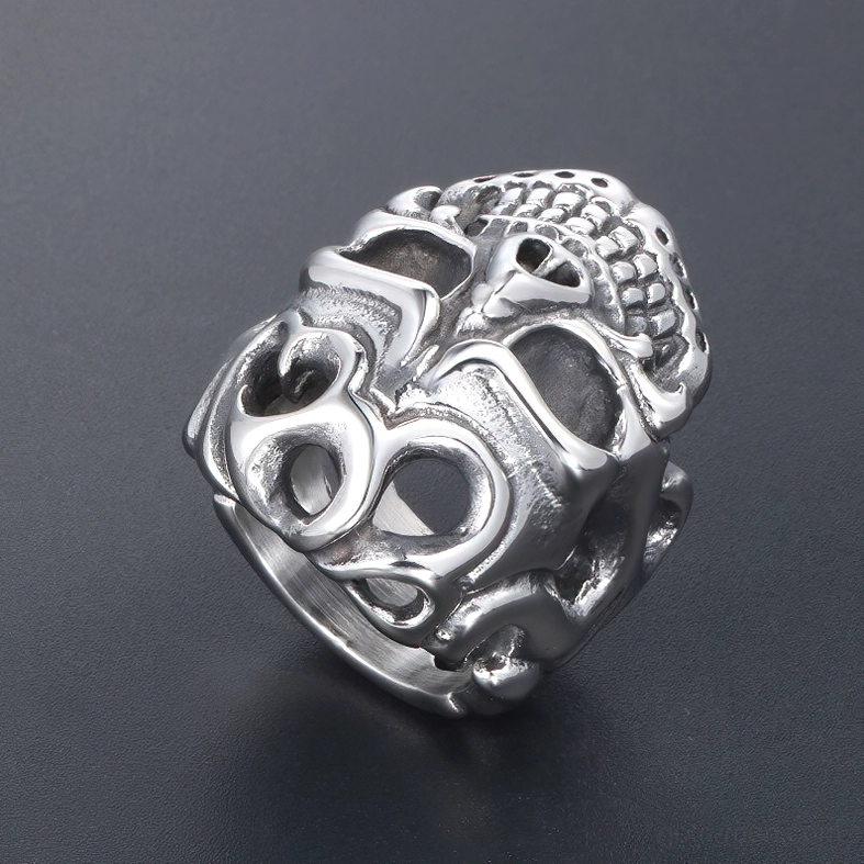 Side perspective view of matte silver finish skull ring against dark gray background with curved hollow cutouts and engraved skull details