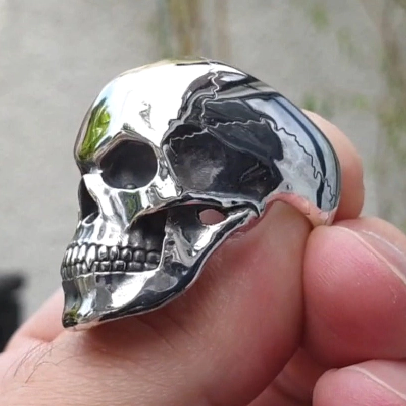 Gothic skull ring worn on finger showing side profile with polished silver tone and engraved crack texture
