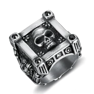 Stainless steel gothic skull ring with geometric frame and black diamond accents, top-left oblique view showing engraved floral side patterns
