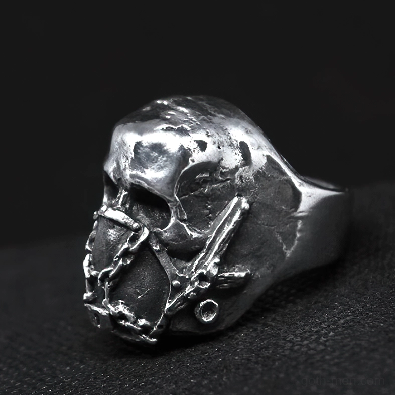 Weathered silver metal gothic skull ring with chain-bound mouth mask, left side 3/4 view showing depth