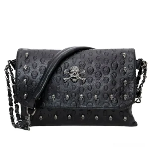 Black gothic leather shoulder bag front view with embossed skull pattern and metal rivet details, flat lay studio photography