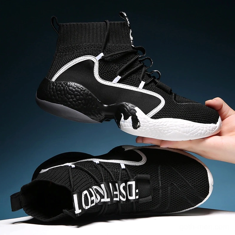 Black gothic high-top sneaker in hand held overhead shot showing white trim and lettered details close-up