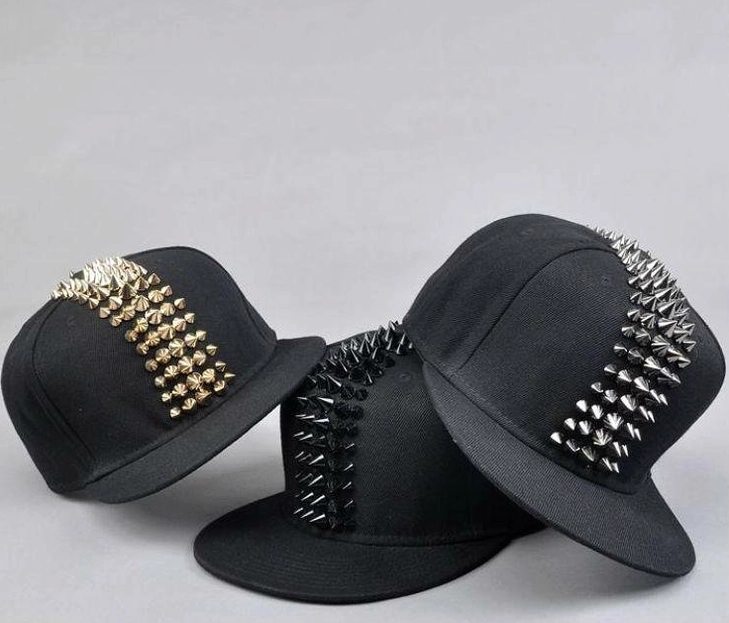 Three gothic spike studded snapback caps in black, silver, and gold metal finishes, flat lay comparison shot