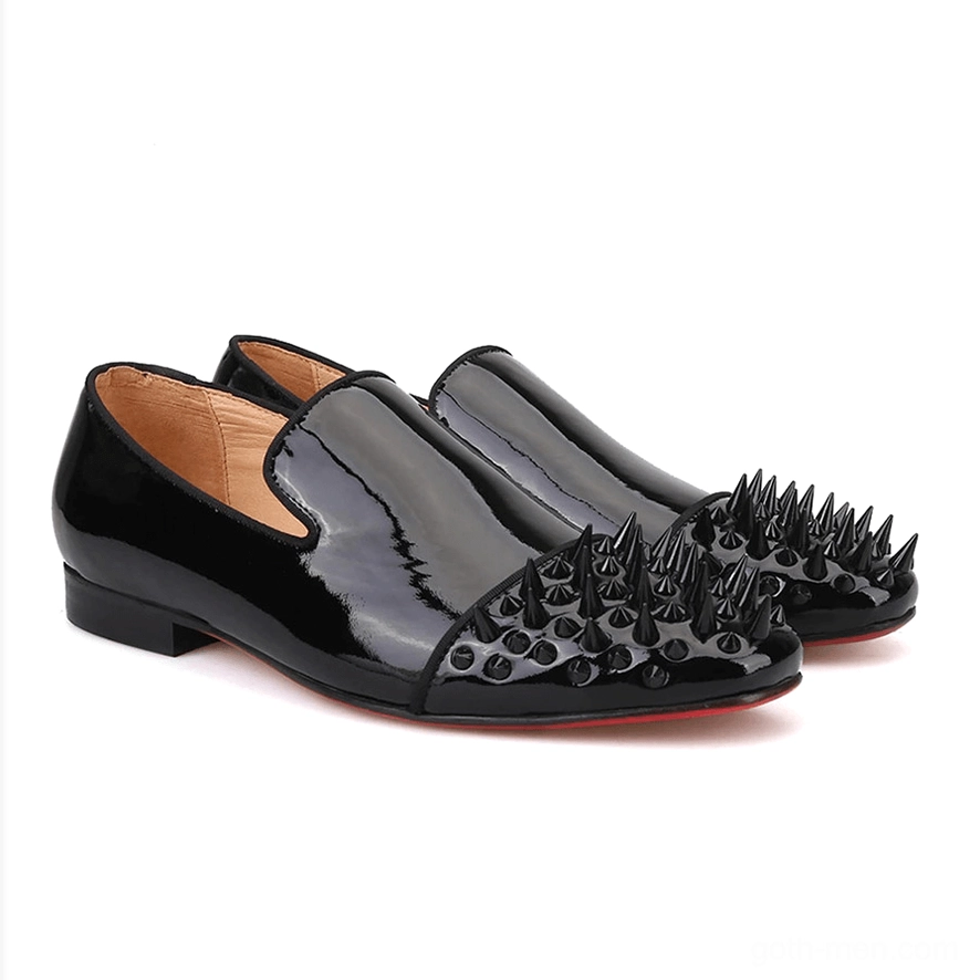 Pair of black patent leather gothic spike loafers in front three-quarter view, highlighting red outsole contrast and geometric spike embellishments