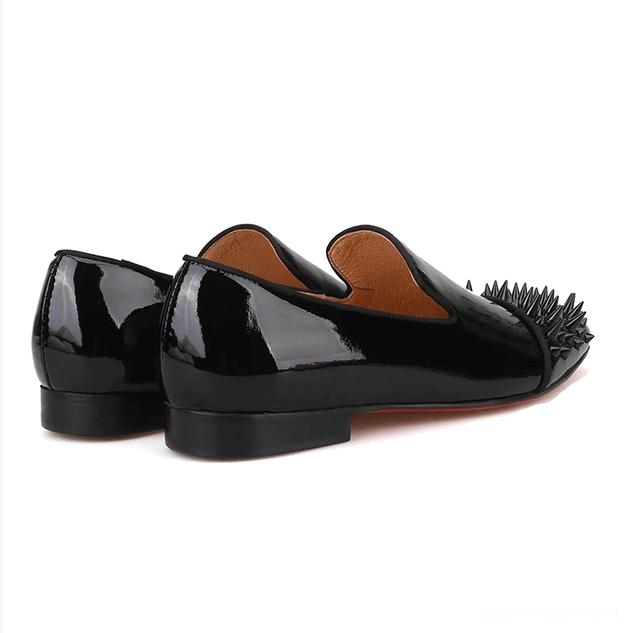 Black patent leather spike loafers rear three-quarter view showing slip-on heel design, spike toe cap, and red bottom sole