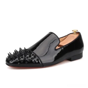 Black patent leather spiked loafers with red outsole, side three-quarter view featuring spike-studded toe cap and gold shoe tree