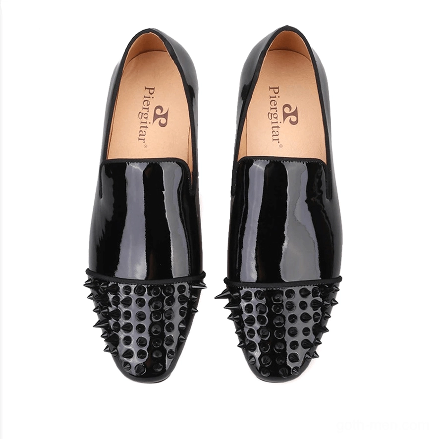 Top-down view of black patent leather spike loafers showing branded insole, spike-studded toe caps, and glossy leather finish