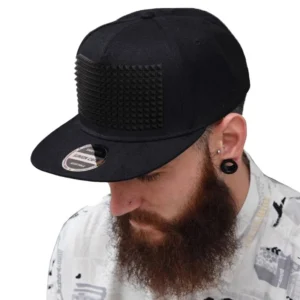 Spike snapback cap worn by bearded model with ear gauges, demonstrating fit and styling with patterned shirt, alternative aesthetic