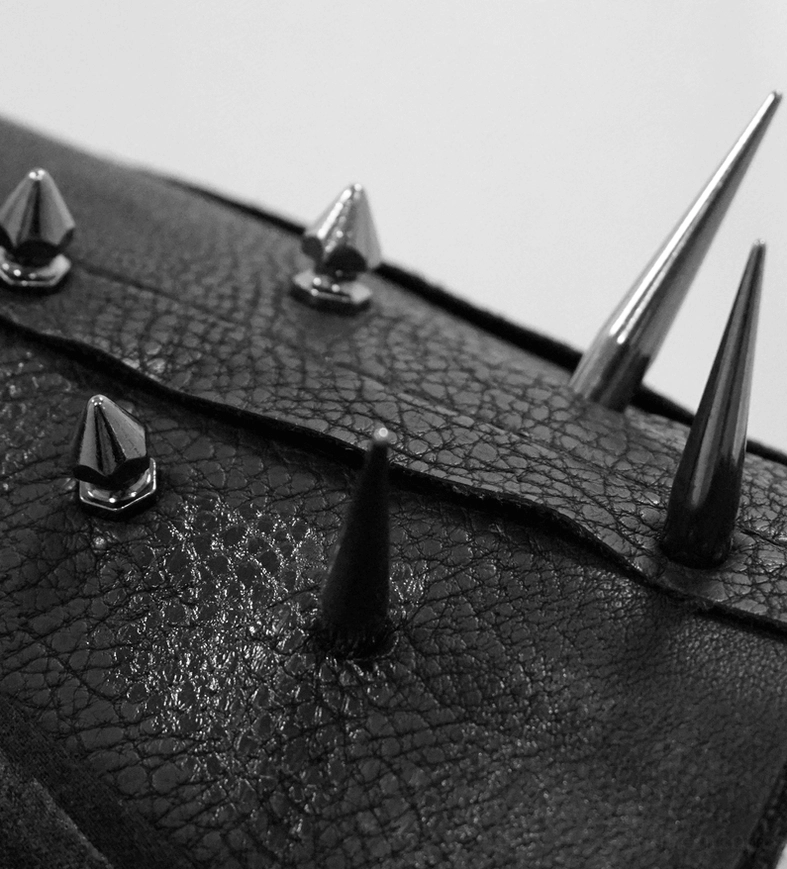 Close-up of mixed gothic punk hardware styles and metal spikes on distressed black fabric